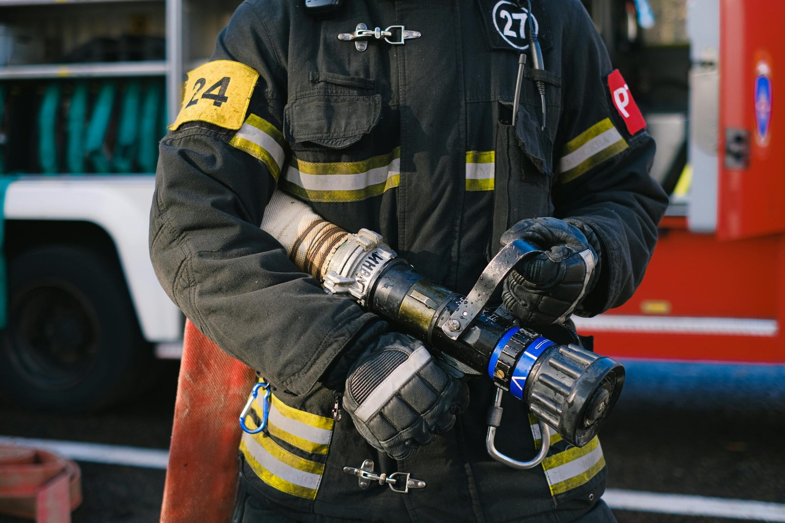 Services Firefighter in protective gear holding a hose nozzle, ready for action.